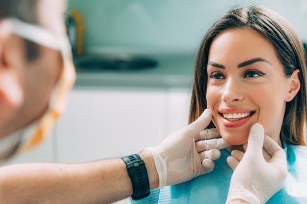 Dentist examines patient's teeth and smile during dental checkup at modern clinic office.