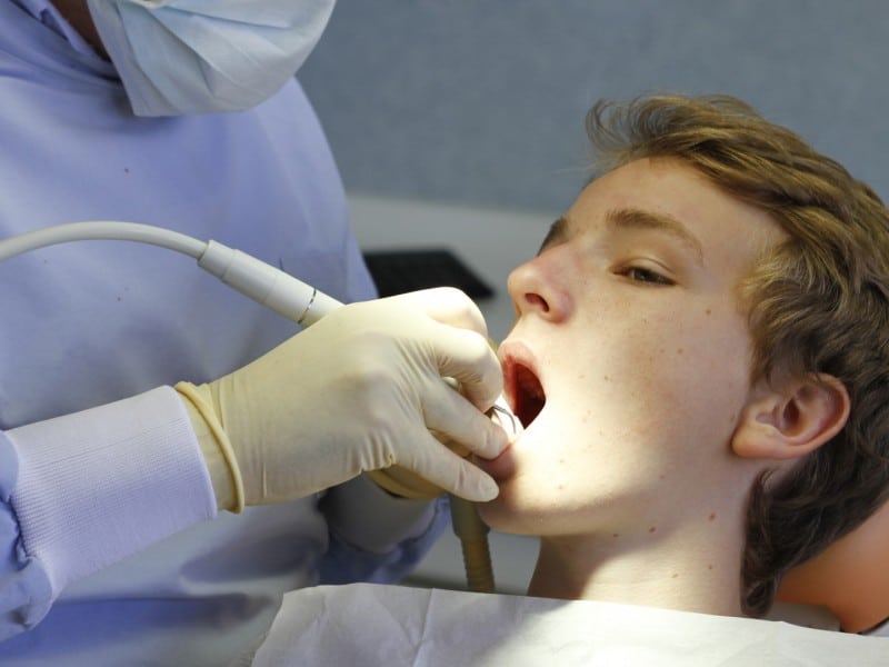 Dentist examining young patient's mouth during dental checkup at clinic.